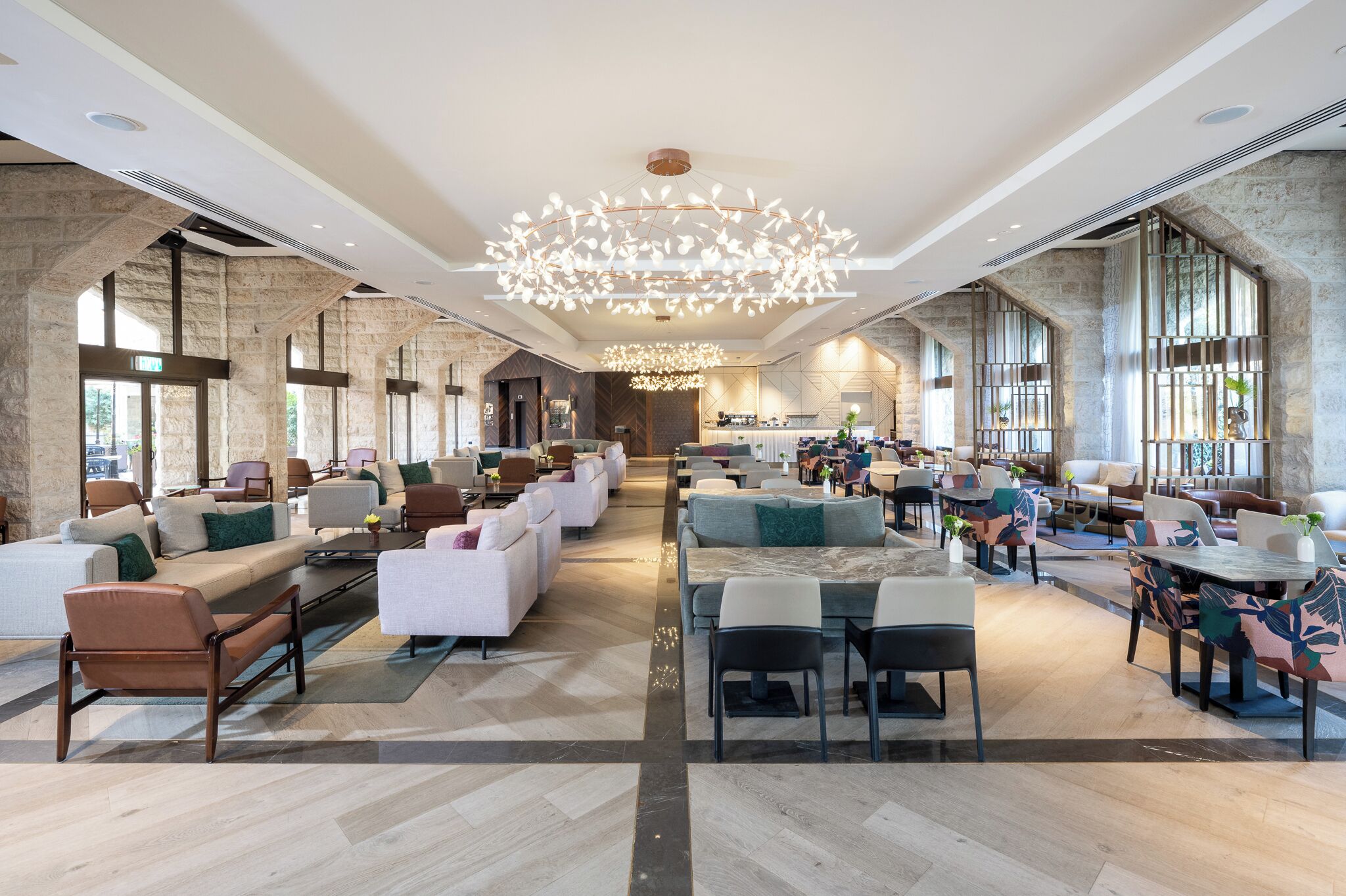 A spacious lobby with modern seating areas, a central chandelier, and large windows providing natural light.