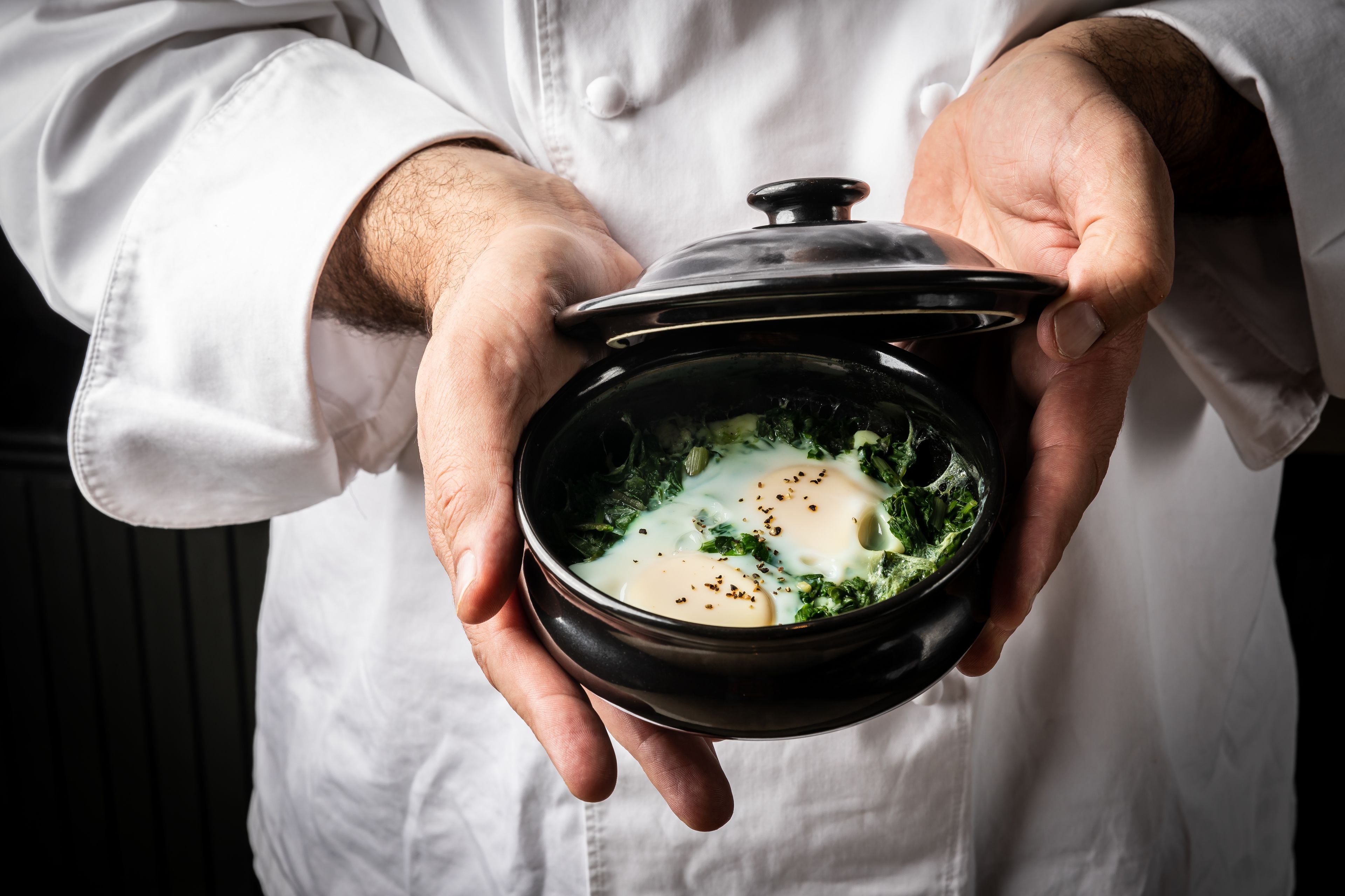 A person holding a bowl of soup with a lid.