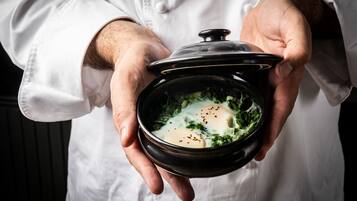 A person holding a bowl of soup with a lid.