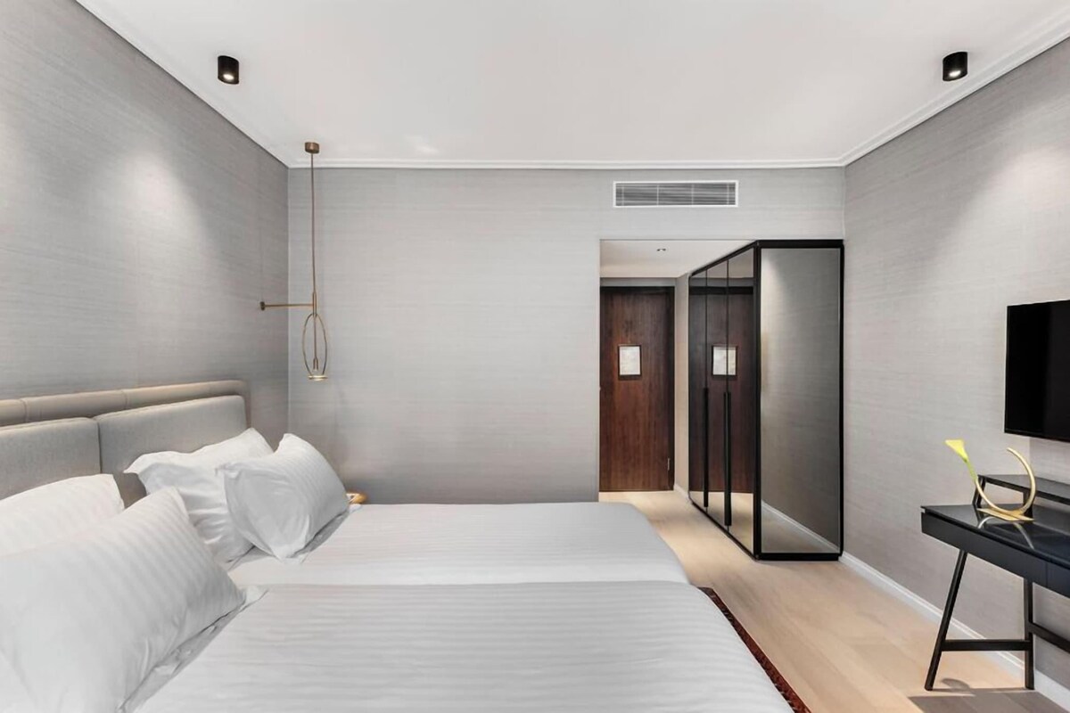 Une chambre d’hôtel moderne dotée d’un grand lit, d’une table de chevet, d’un téléviseur à écran plat et d’un dressing.