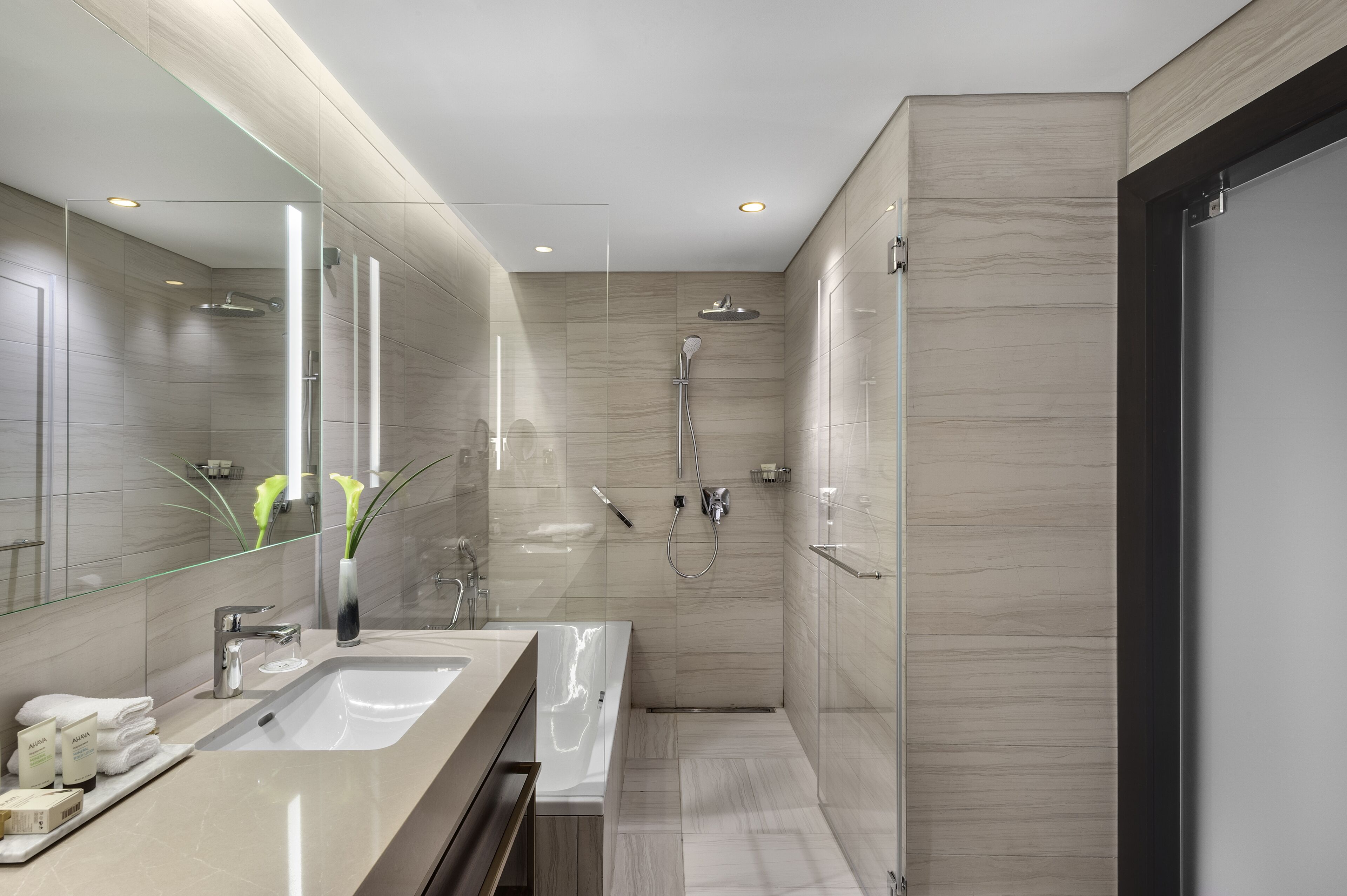 A modern bathroom with a large mirror, a sink, a bathtub, and a shower.