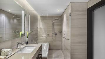 A modern bathroom with a large mirror, a sink, a bathtub, and a shower.