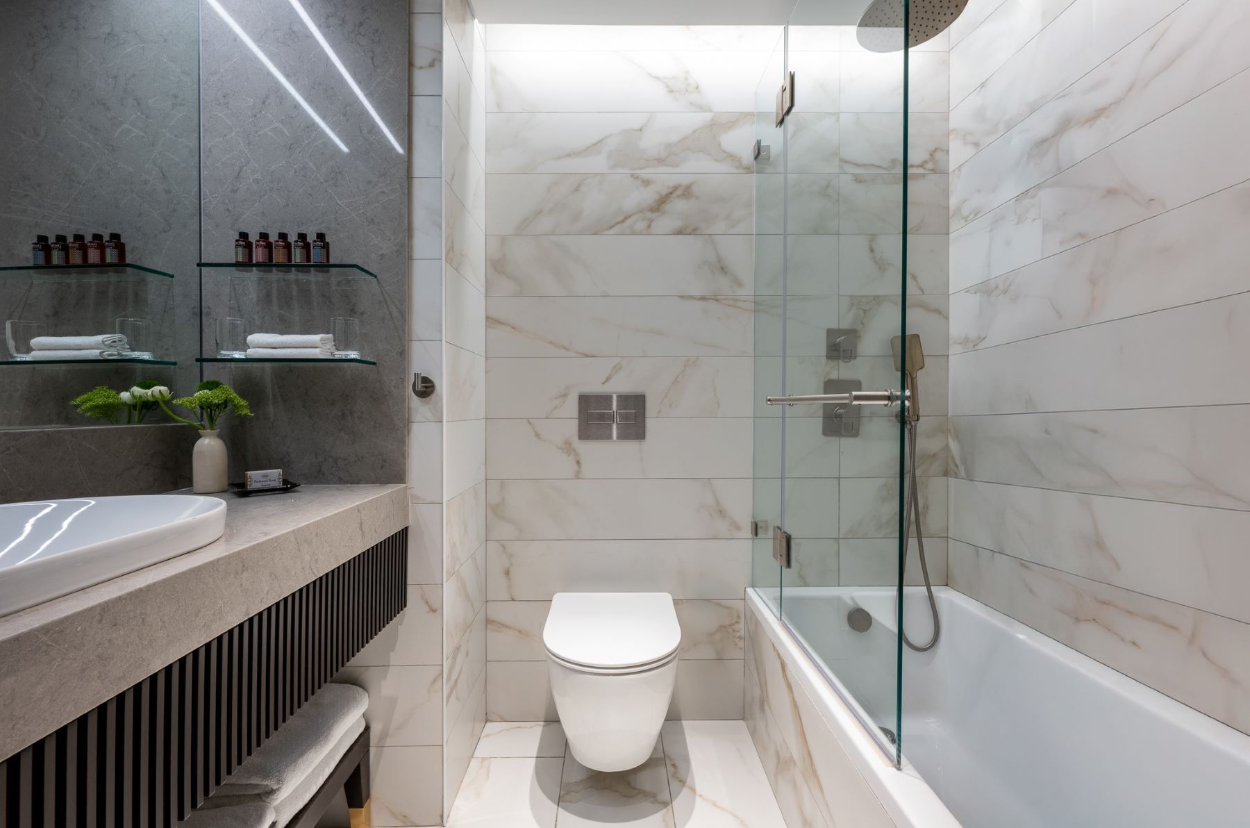 Un baño moderno con cabina de ducha de vidrio, inodoro blanco y azulejos de mármol.