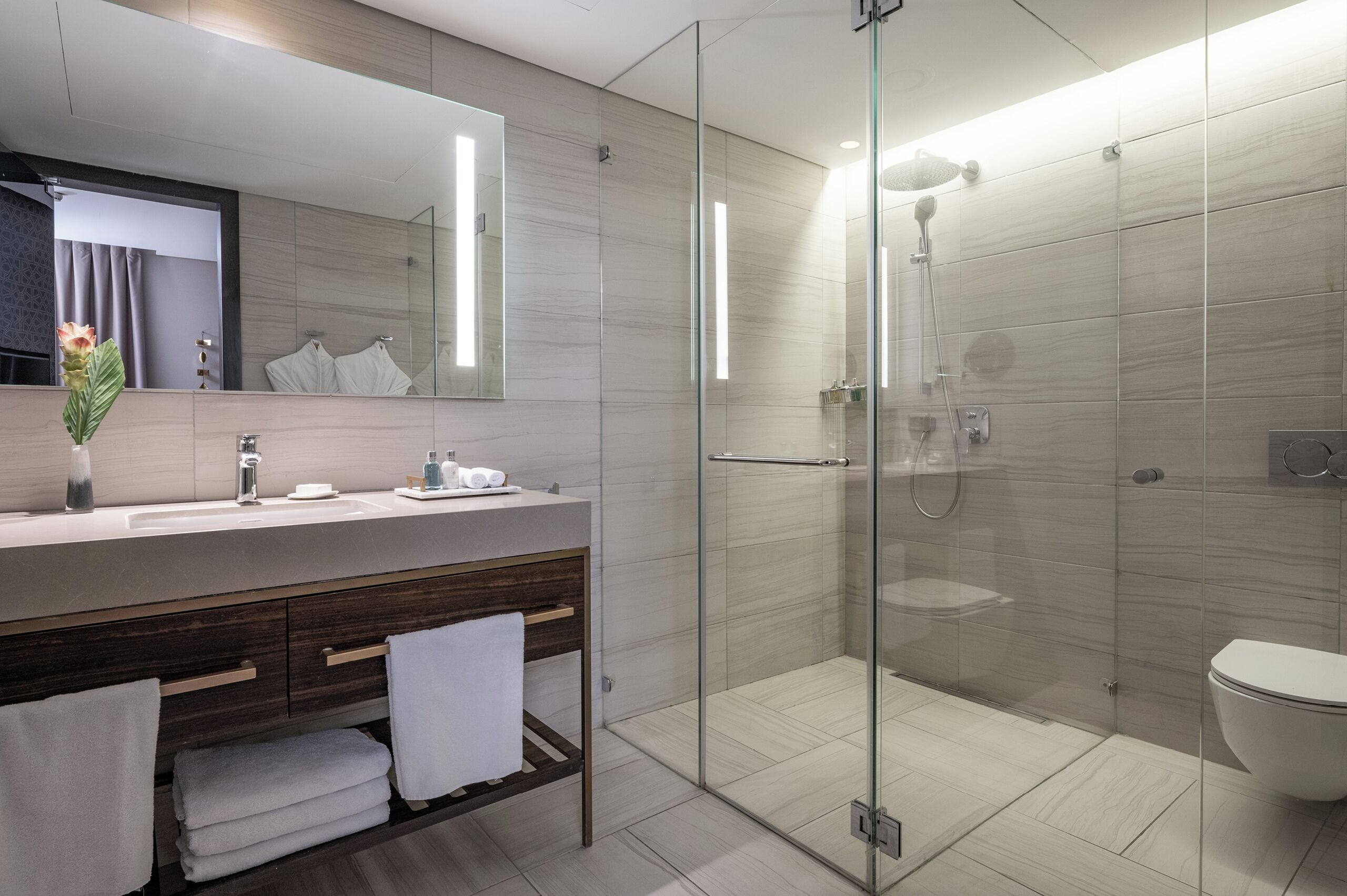 A modern bathroom with a glass-enclosed shower, a vanity with a mirror, and a toilet.