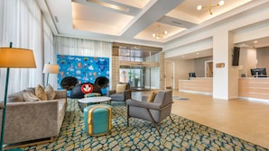 A spacious lobby with a modern design, featuring a seating area with sofas and armchairs, a patterned carpet, and a reception desk. - Holiday Inn Orlando - Disney Springs® Area by IHG (Lake Buena Vista)