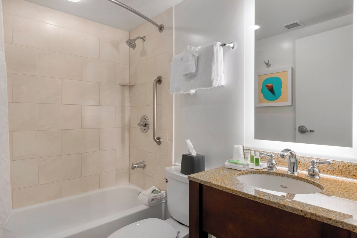 A bathroom with a bathtub, toilet, sink, and a shower with grab bars.