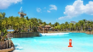 Un complexe hôtelier tropical doté d’une piscine à l’eau cristalline, de palmiers et d’un panneau indiquant « Interdiction de plonger ».