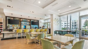 A modern restaurant with a bar area, multiple seating options, and large windows offering a view of the outside. - Holiday Inn Orlando - Disney Springs® Area by IHG (Lake Buena Vista)