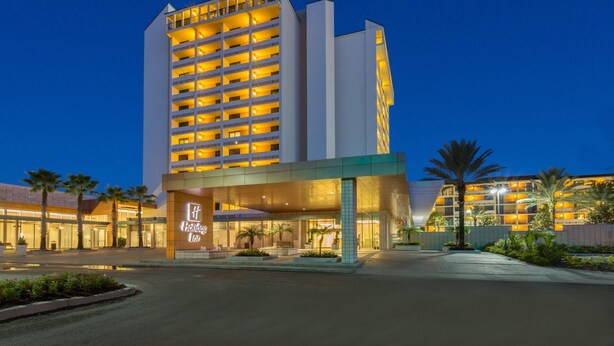 A multi-story hotel with a prominent entrance and a well-lit facade. - Holiday Inn Orlando - Disney Springs® Area by IHG (Lake Buena Vista)
