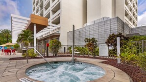 A hot tub with a sign indicating a depth of 3 feet and a height of 9 feet, surrounded by a pool area with a fence, palm trees, and a building in the background. - Holiday Inn Orlando - Disney Springs® Area by IHG (Lake Buena Vista)