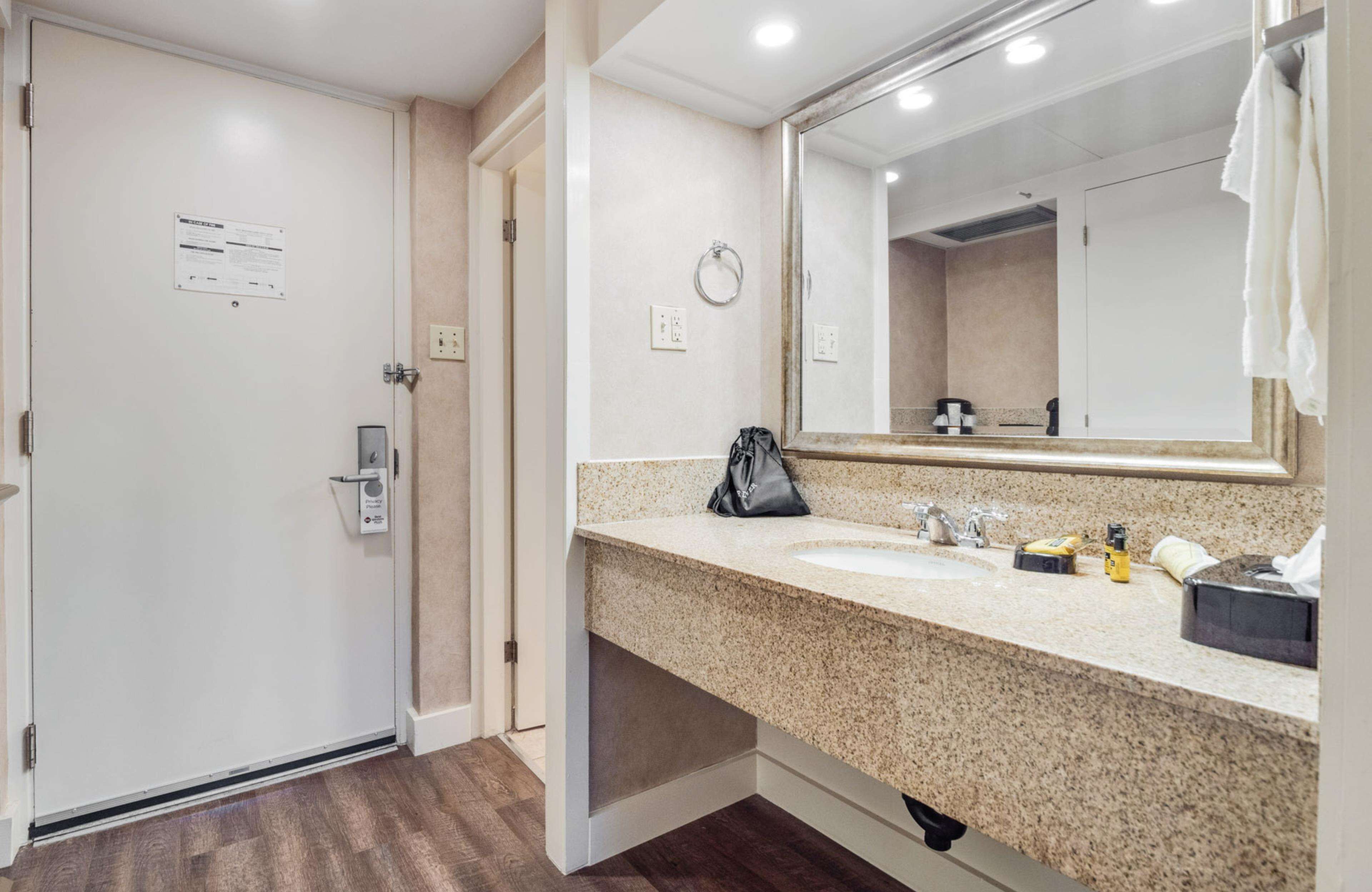 A bathroom with a granite countertop, a sink, a mirror, and a towel rack.