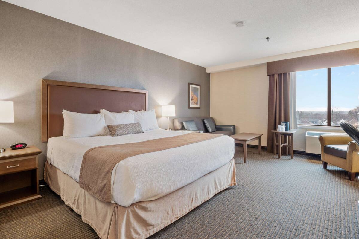 A hotel room with a large bed, a desk, a chair, and a window with a view.