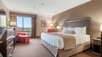 A hotel room with a large bed, a desk, a chair, and a dresser.