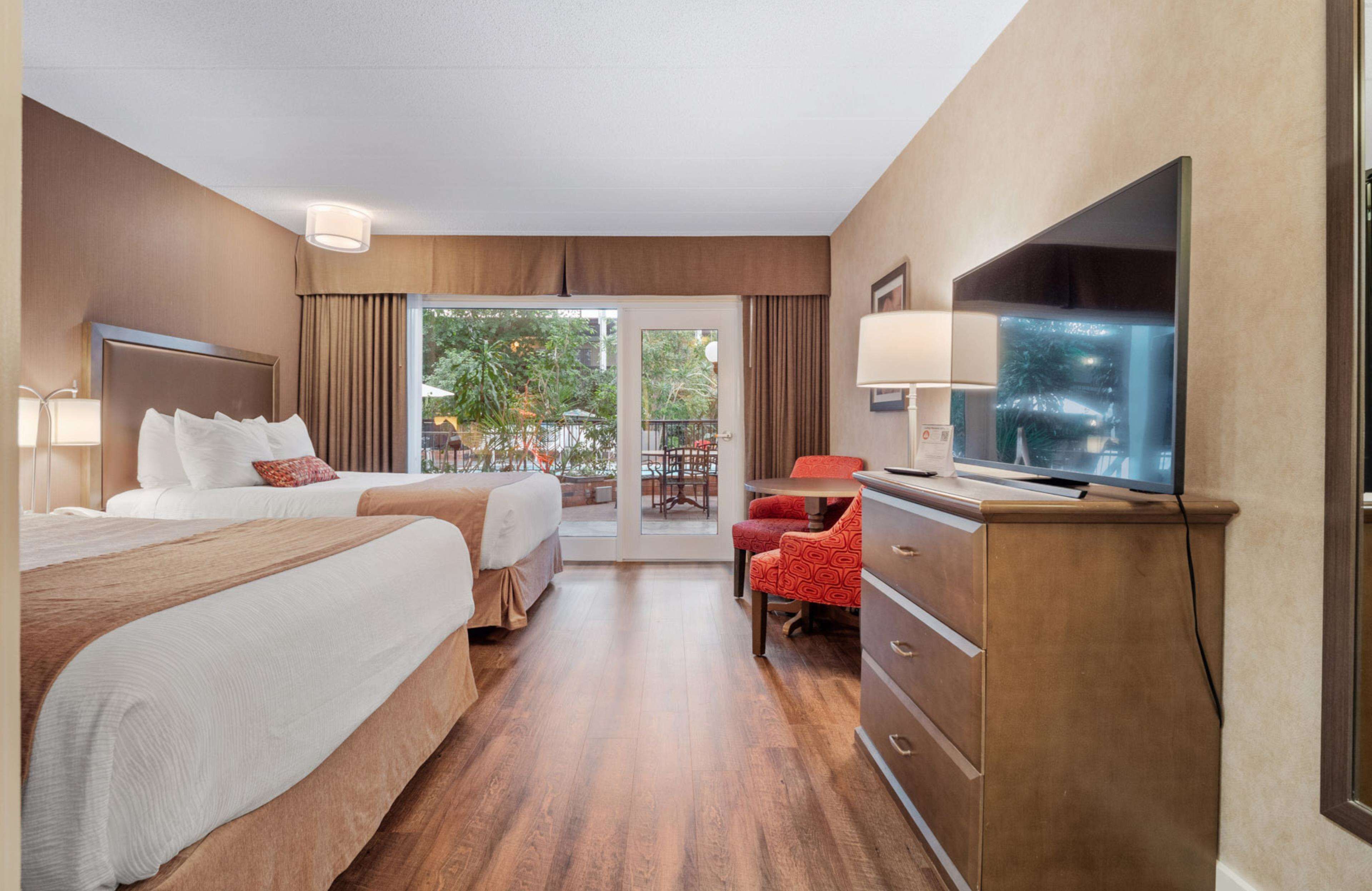 Une chambre d’hôtel avec deux lits, une télévision, un bureau et une chaise.