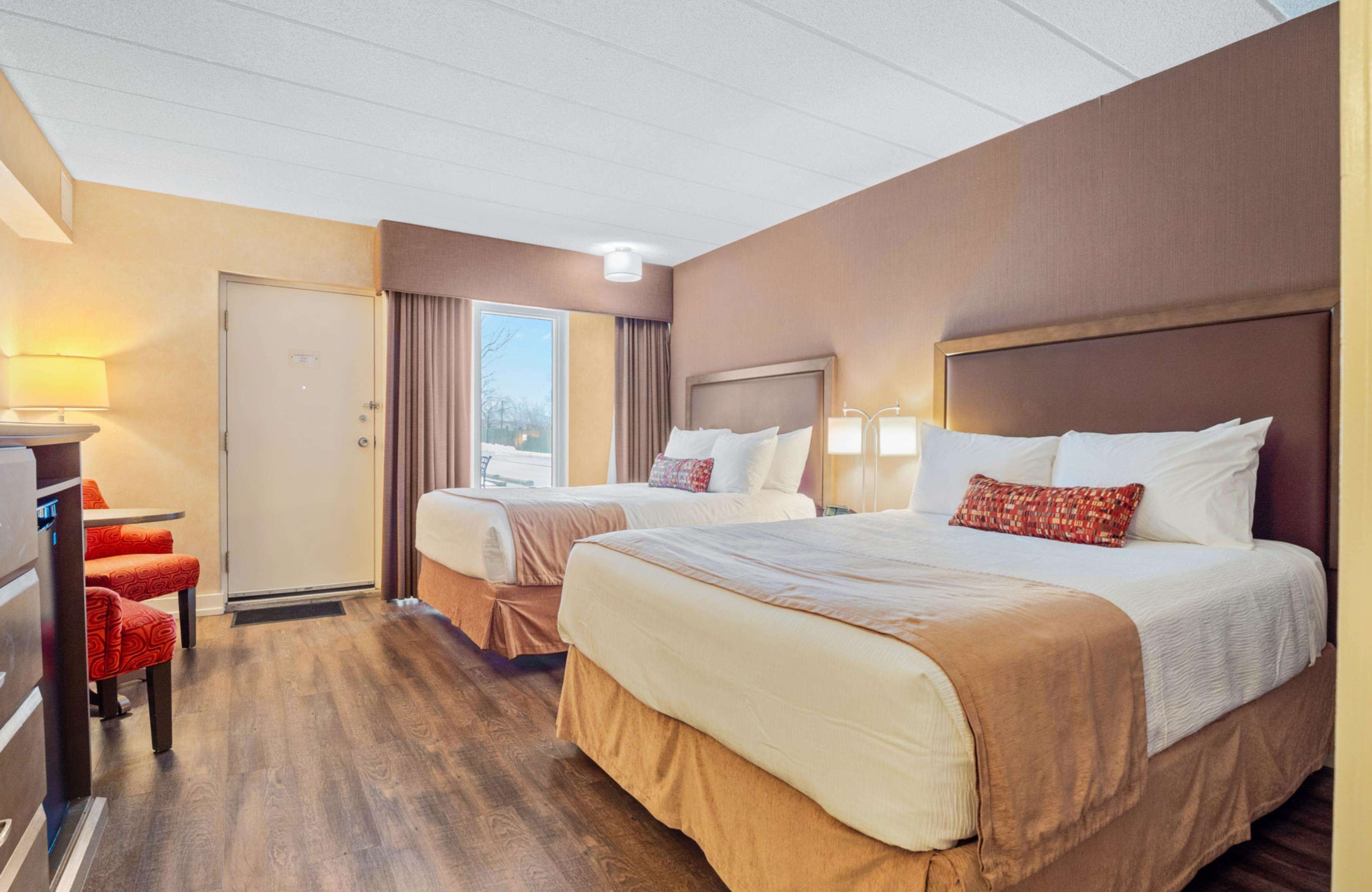 A hotel room with two beds, a desk, and a chair.