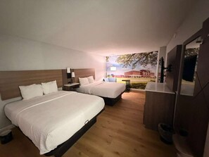 Une chambre d’hôtel avec un grand lit, une table de chevet, une petite table et un miroir.