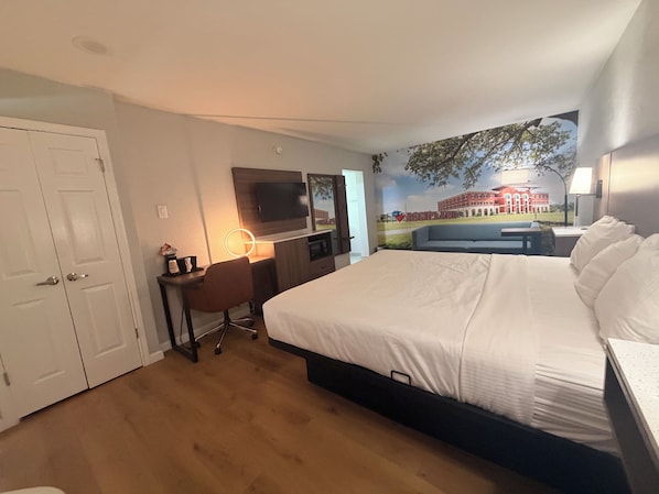 Une chambre d’hôtel avec un lit, un bureau, une chaise, une télévision et une fresque murale.