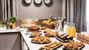 Un buffet per la colazione con dolci, frutta e bevande.