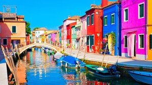 A canal with colorful buildings on either side, a bridge, and boats docked along the water. - Ambasciatori Hotel Mestre Venice, Tapestry Collection by Hilton (Mestre)
