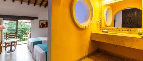 A hotel room with a balcony, a bathroom with a large mirror, and a table with chairs.
