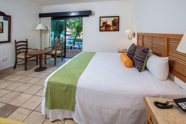 Habitación de hotel con cama, escritorio con sillas, teléfono y vista al área exterior.