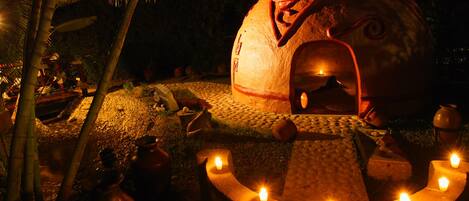 Una estructura abovedada con un diseño tallado, rodeada por un sendero de piedra con velas.