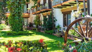 Un edificio con varios balcones, abundante vegetación y una gran rueda de madera.