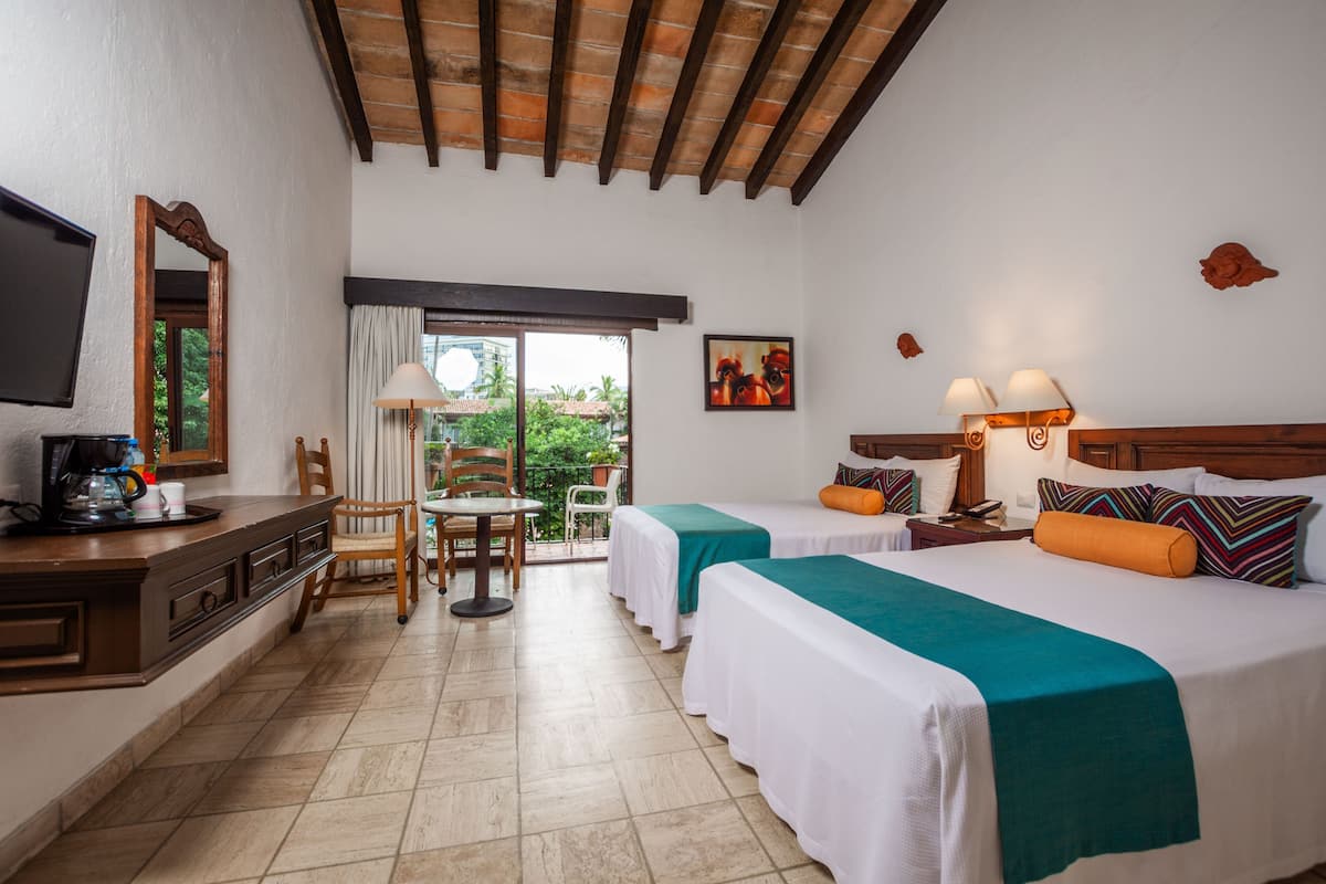 Une chambre d’hôtel avec deux lits, un bureau avec une machine à café, une chaise, une table et une vue sur l’extérieur.