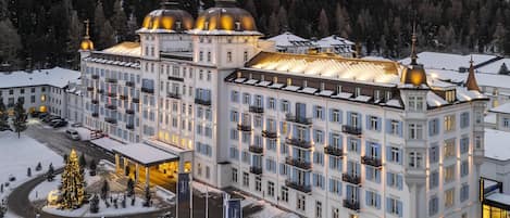 A large, multi-story hotel with a symmetrical facade, multiple balconies, and a central courtyard with a Christmas tree.