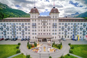 A large hotel with two prominent domed towers, a central entrance, and a well-maintained outdoor seating area. - Grand Hotel des Bains Kempinski (St. Moritz)