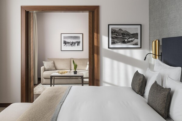 A hotel room with a bed, a sofa, a coffee table, and two framed pictures on the wall.