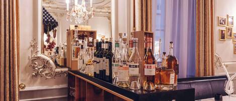 A bar area with a variety of liquor bottles, a chandelier, and a mirror reflecting the room's decor.