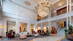 A grand lobby with a chandelier, seating areas, and a staircase.