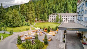 A hotel with a courtyard, outdoor seating, and a mountain backdrop. - Grand Hotel des Bains Kempinski (St. Moritz)