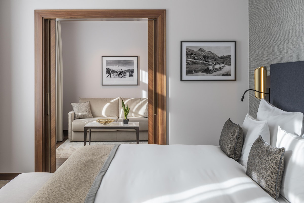 Una habitación de hotel con cama, sofá, una mesita de café y dos cuadros en la pared.
