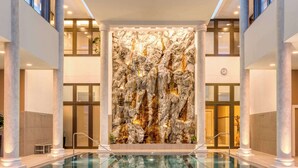 A spacious indoor swimming pool with a rocky wall in the background.