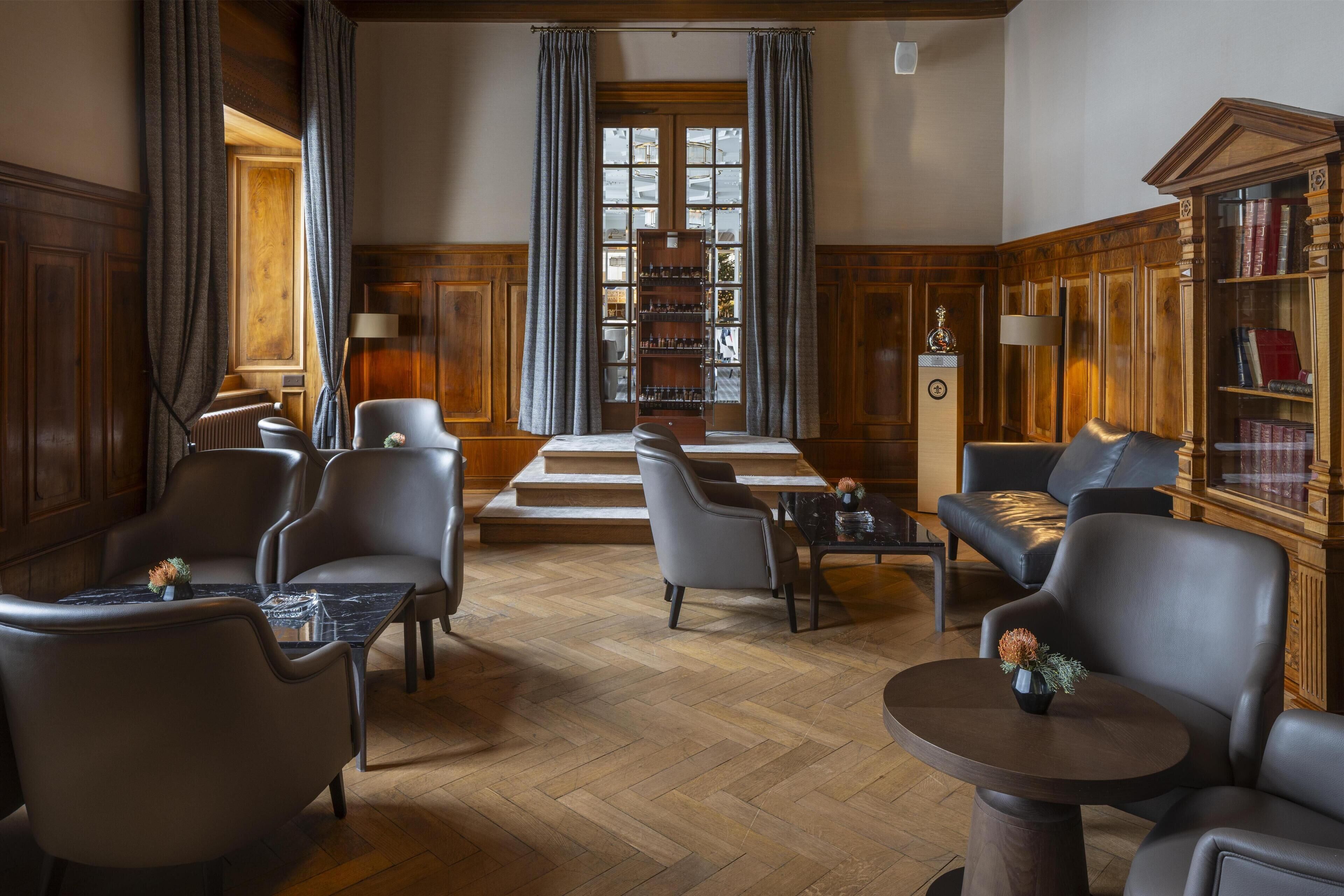 Une bibliothèque avec des fauteuils en cuir, des tables en bois et des étagères.