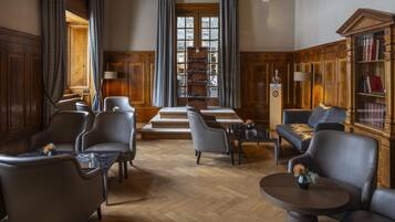 Une bibliothèque avec des fauteuils en cuir, des tables en bois et des étagères.