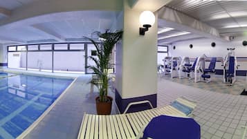 An indoor swimming pool with exercise equipment and a potted plant.