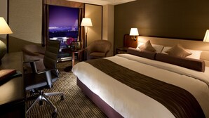 Une chambre d’hôtel avec un grand lit, deux chaises, un bureau et une table de chevet.