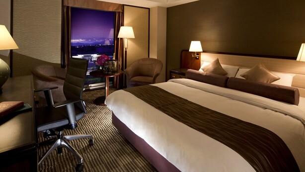 Een hotelkamer met een groot bed, twee stoelen, een bureau en een nachtkastje.