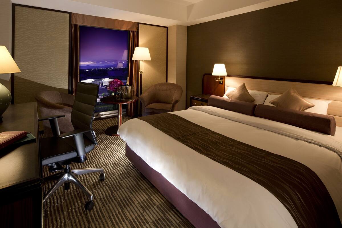 A hotel room with a large bed, two chairs, a desk, and a nightstand.