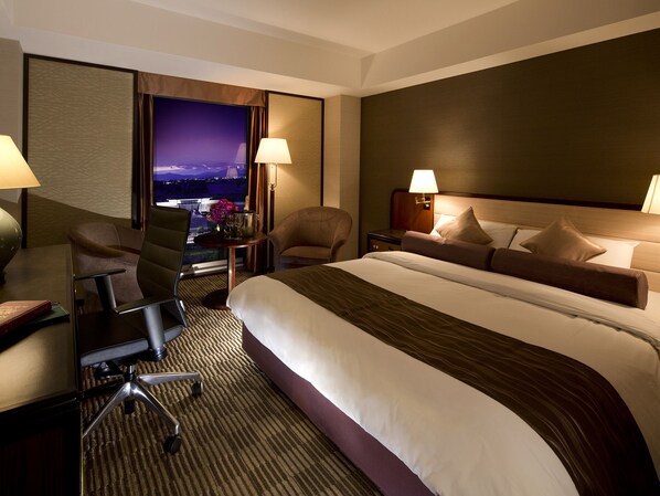 Une chambre d’hôtel avec un grand lit, deux chaises, un bureau et une table de chevet.