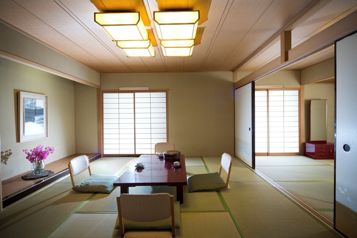 Une pièce de style japonais traditionnel, avec un sol recouvert de tatamis, une table basse et des paravents en papier de riz (shoji).