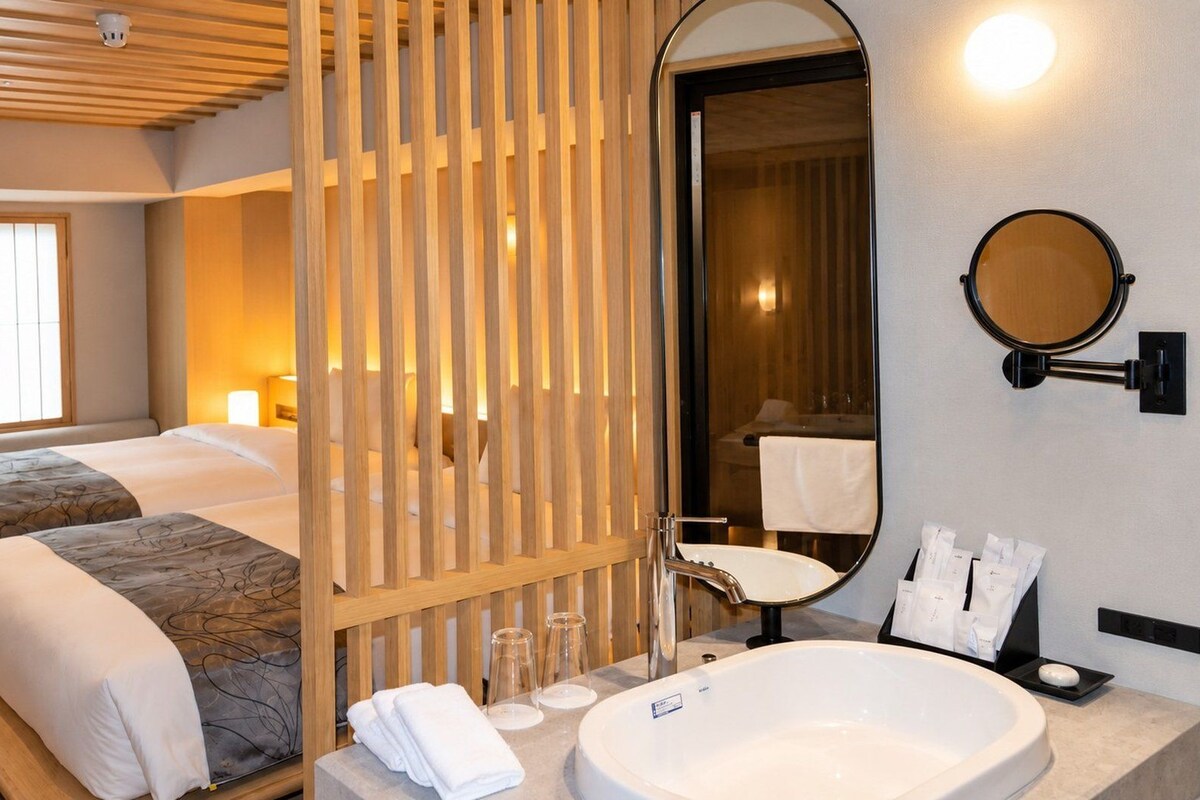 A hotel room with two beds, a large bathroom with a bathtub, and a wooden partition.