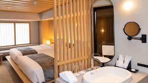 Habitación de hotel con dos camas, un baño amplio con bañera y un separador de madera.