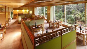 Un restaurant traditionnel de style japonais, avec des tatamis, des tables en bois et une vue sur les arbres environnants.