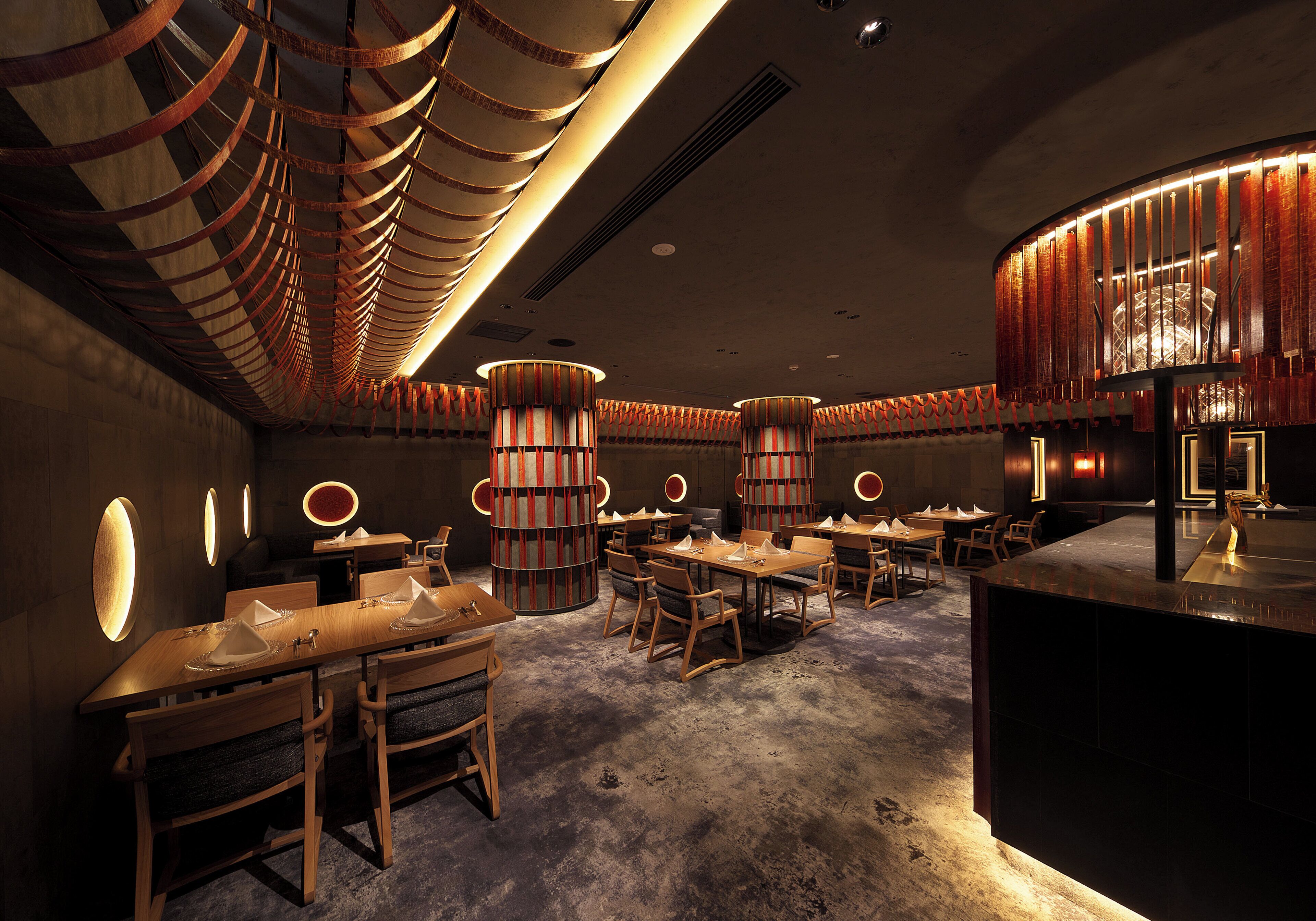 A restaurant interior with multiple dining tables, chairs, and a central decorative column.