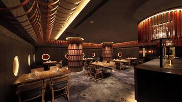 A restaurant interior with multiple dining tables, chairs, and a central decorative column.