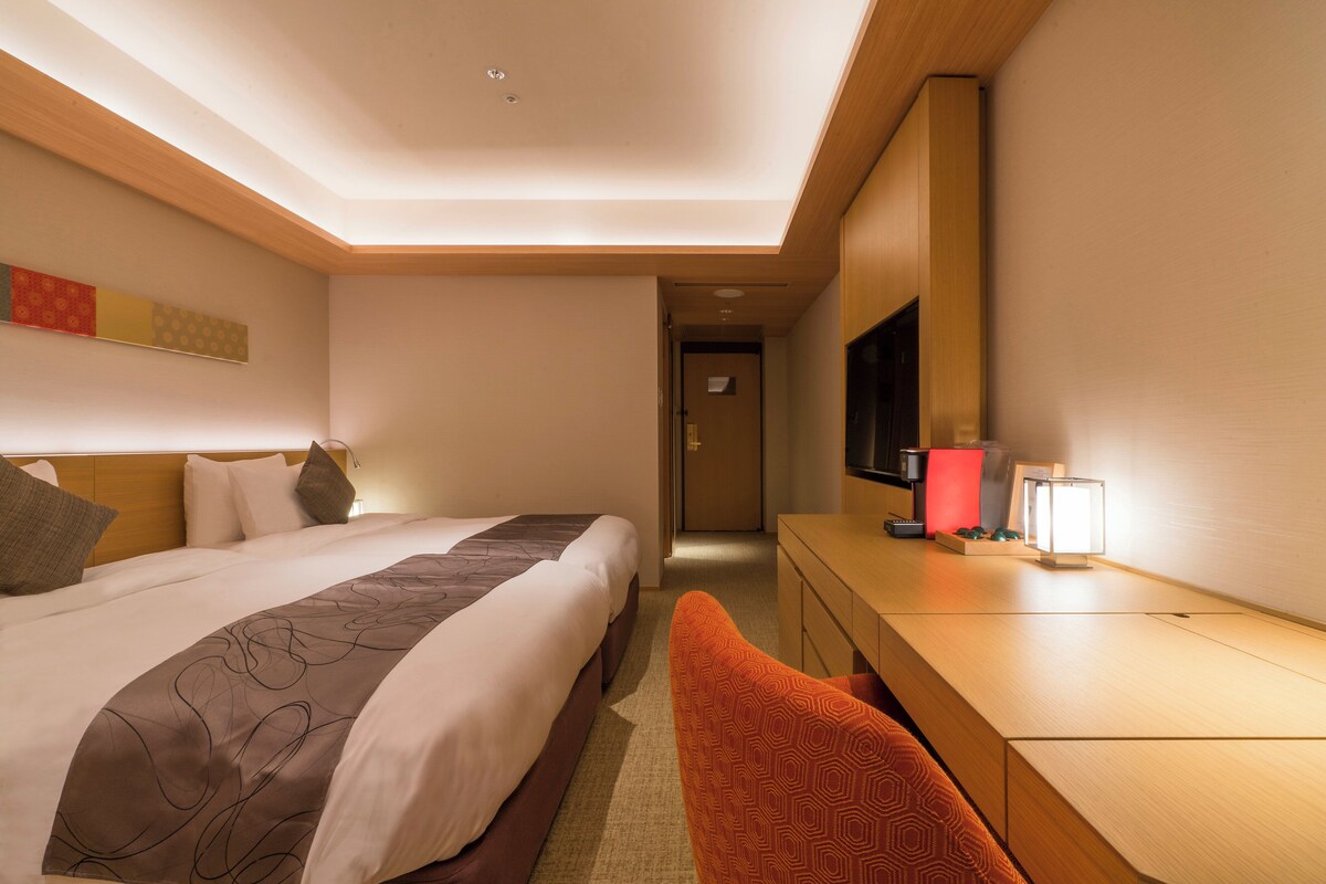 Une chambre d’hôtel avec un lit, un bureau, une chaise, une télévision et une lampe.